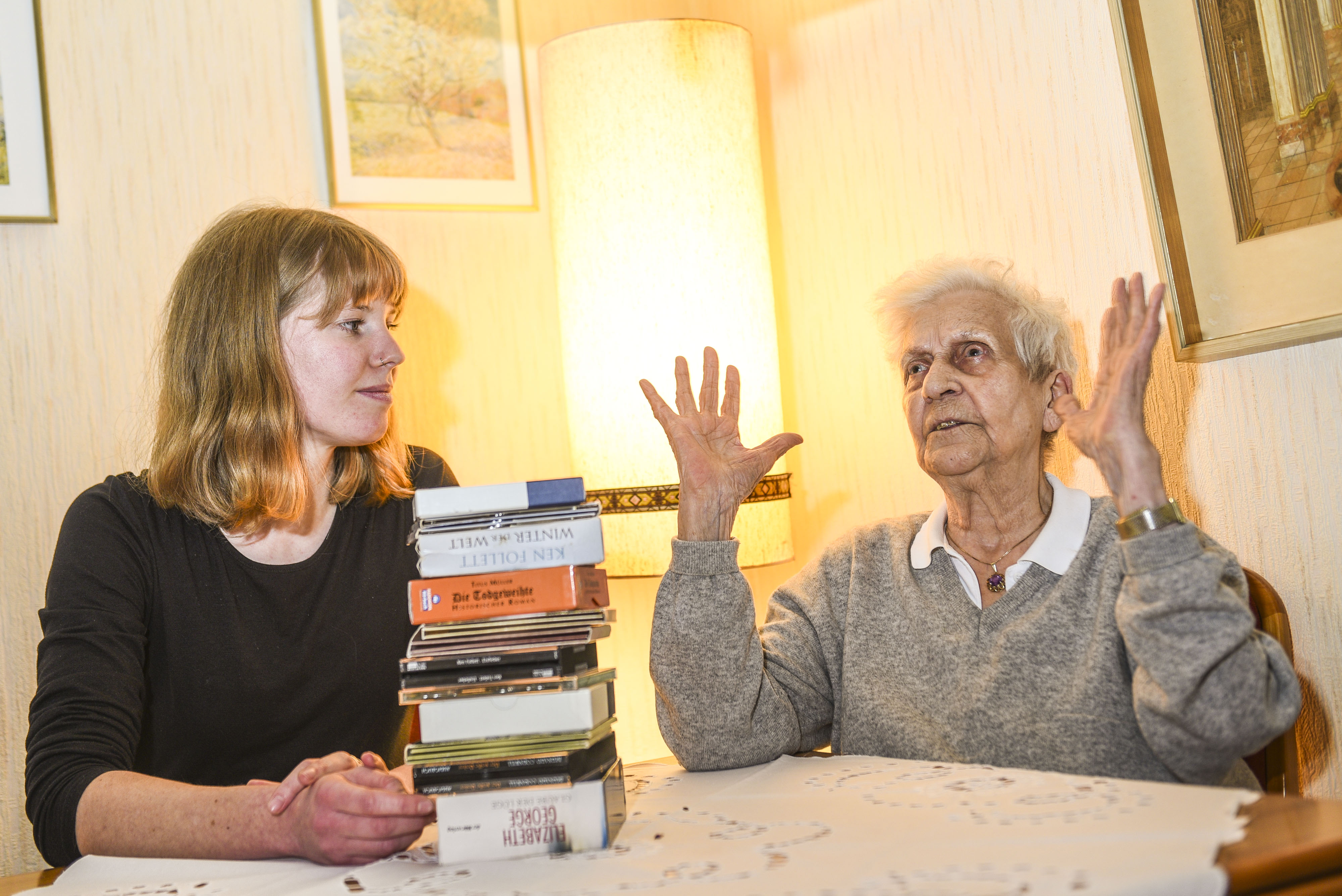 Foto: Junge Frau und ältere Frau mit Bücherstapel