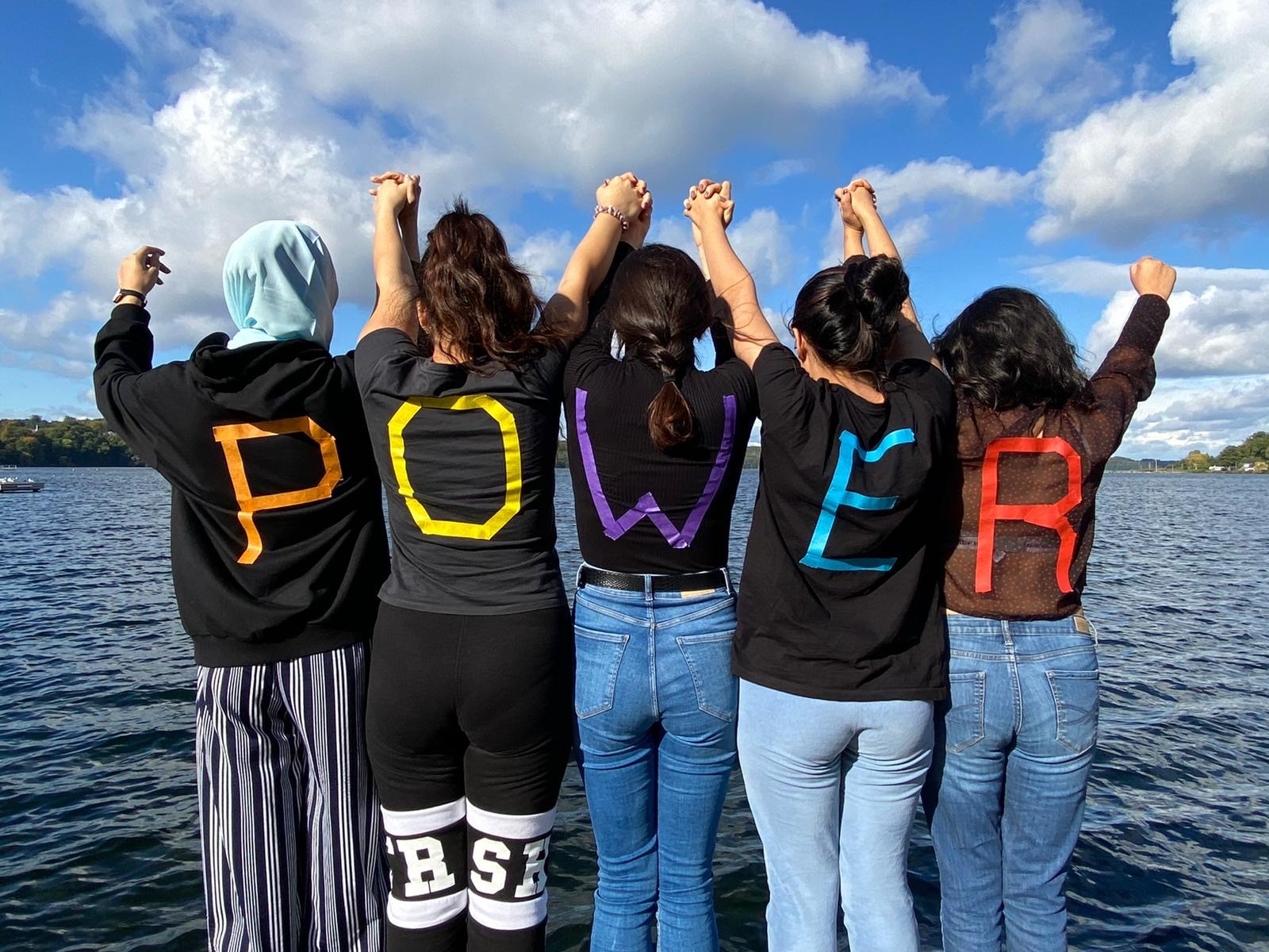 Foto fünf junge Frauen haben die Buchstaben des Worts Power auf ihren Rücken