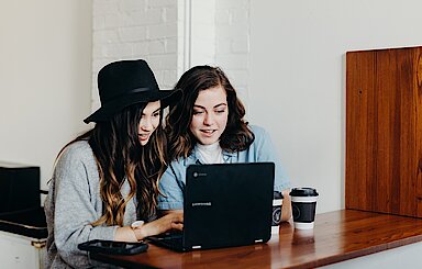 Foto: Zwei Frauen sitzen vor einem Laptop