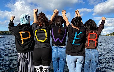 Foto fünf junge Frauen haben die Buchstaben des Worts Power auf ihren Rücken